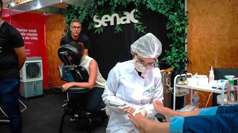 Profissional do Senac realiza atendimento de podologia em visitante durante a Expocrato 2026, no estande do Sesc e Senac Ceará.
