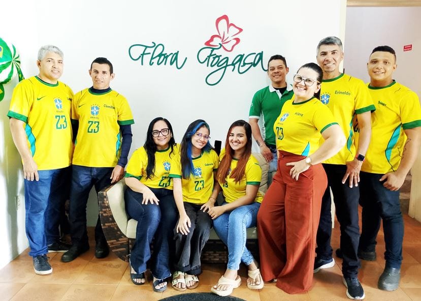 Equipe da loja Flora Fogaça reunida em frente ao logotipo da marca, celebrando a trajetória da empresa de produtos regionais na Ibiapaba, Ceará